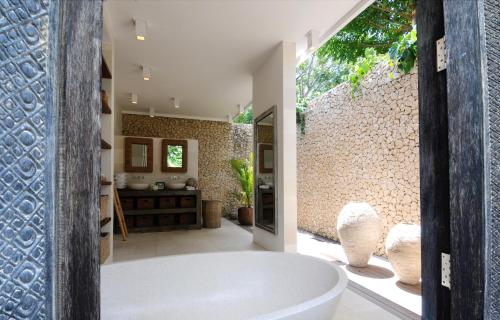 ein Badezimmer mit einer Badewanne und einer Steinmauer in der Unterkunft Jeda Villa Modern Stylish Luxury Villa in Pemuteran