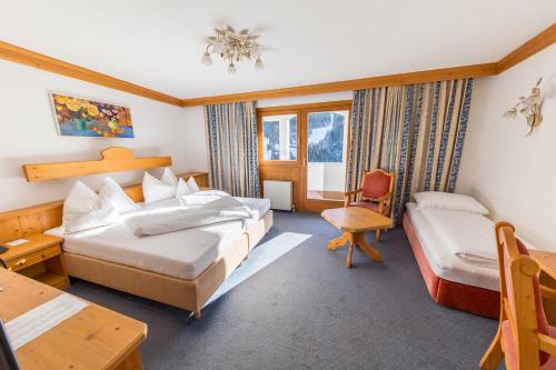a hotel room with two beds and a desk at Hotel Karl Schranz in Sankt Anton am Arlberg
