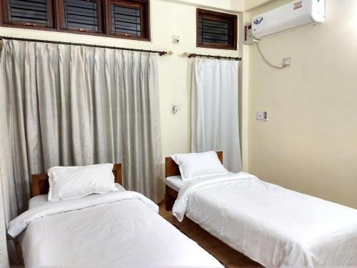 dwa łóżka w pokoju z oknem w obiekcie Tranqville w mieście Guwahati