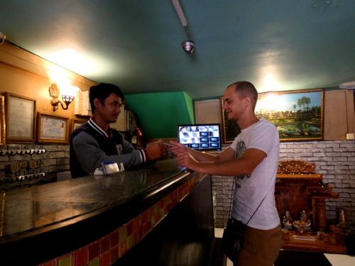 two men standing at a bar in a pub at Pich Guesthouse in Phnom Penh