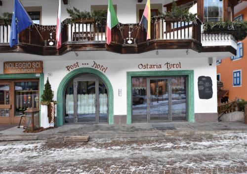 a building with two doors and a balcony at Post Hotel Moena in Moena