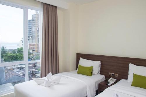 2 bedden in een hotelkamer met een raam bij Green Eden Hotel in Manado