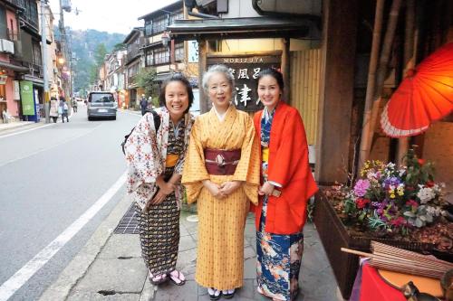 three women standing on a sidewalk in front of a building at Morizuya in Toyooka