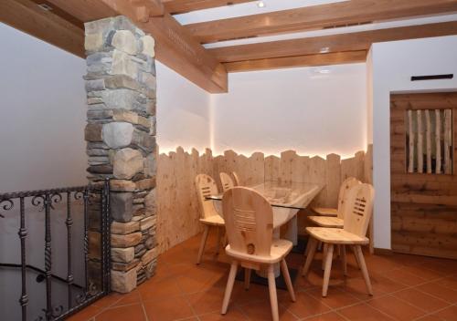 a dining room with a table and chairs and a stone wall at Post Hotel Moena in Moena