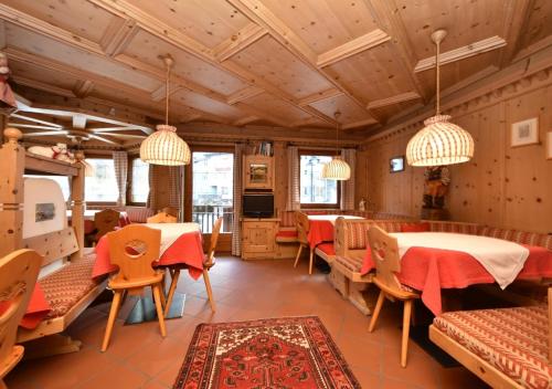 a restaurant with wooden ceilings and tables and chairs at Post Hotel Moena in Moena