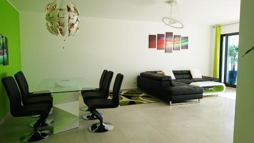a living room with a glass table and black chairs at Apartamento Doreen in Caniço