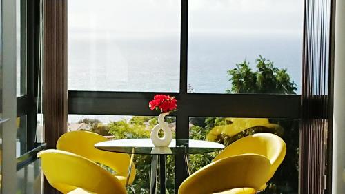 stół i żółte krzesła przed oknem w obiekcie Apartamento Doreen w Caniço