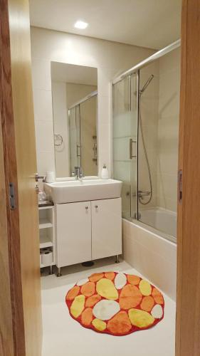 a bathroom with a sink and a shower and a rug at Apartamento Doreen in Caniço