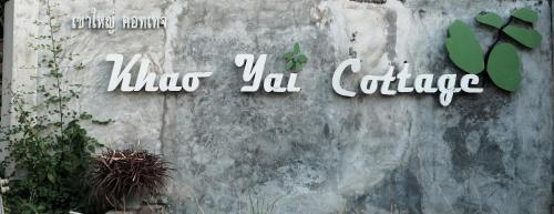 a sign on the side of a wall with plants at Khao Yai Cottage in Mu Si