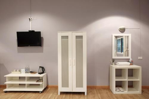 a room with two white shelves and a tv on a wall at Khao Yai Cottage in Mu Si