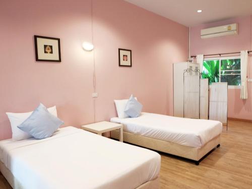 two beds in a room with pink walls at Khao Yai Cottage in Mu Si