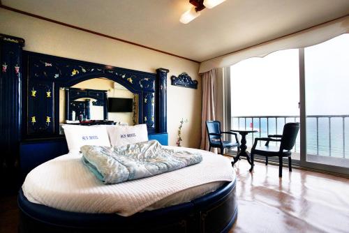 a bedroom with a bed and chairs and a balcony at Sun Motel in Gangneung