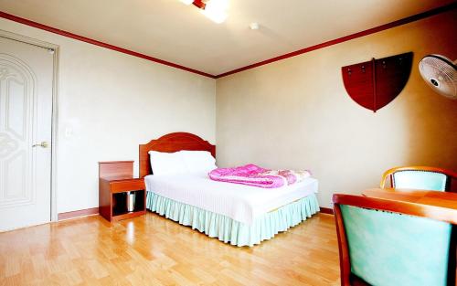 a bedroom with a bed with white sheets and a wooden floor at Sun Motel in Gangneung