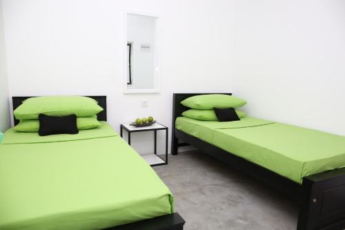 two beds in a room with green sheets and pillows at THE CLASSIC-Hostel-apartment-Standard Room in Weligama