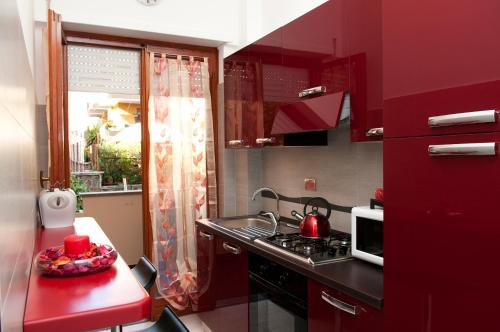 una pequeña cocina con armarios rojos y fregadero en La Casetta del Vaticano, en Roma