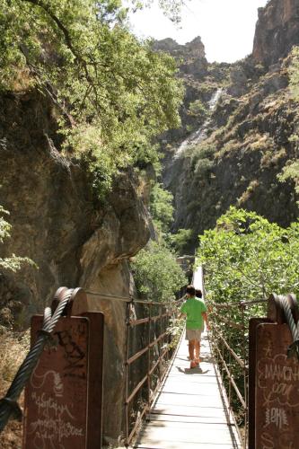 a person walking across a bridge in a canyon at Hotel Rural Huerta del Laurel in Monachil