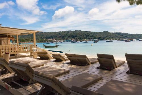 a deck with chairs and boats in the water at Mama Beach Residence - Adults Only in Phi Phi Don