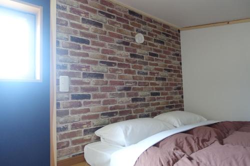 a bedroom with a brick wall and a bed with pillows at Stay Nikko Guesthouse in Nikko