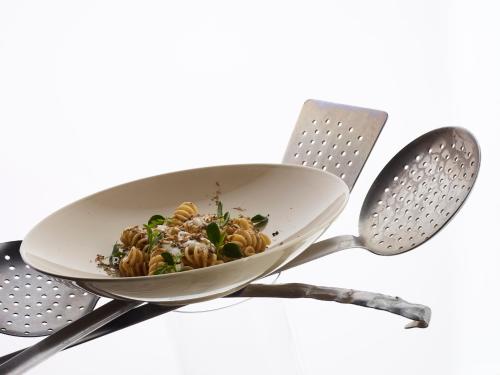 a bowl of pasta on a strainer with two utensils at Hotel Ristorante Eurossola in Domodossola