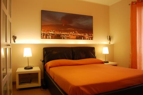 um quarto com uma cama com lençóis laranja e 2 candeeiros em B&B Prima Classe em Belpasso