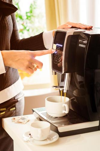 a woman is pouring coffee into a coffee maker at Marlin Rooms in Cagliari