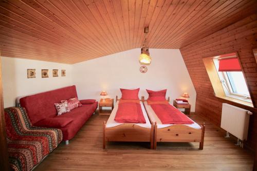 sala de estar con 2 camas y sofá rojo en Ferienhaus Frei 2 Titisee, en Titisee-Neustadt