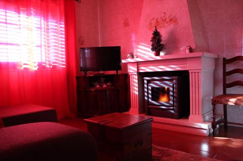a red living room with a fireplace and a tv at Casa da tia Bina in Monsaraz