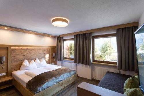 a hotel room with a bed and two windows at Naturlodge Ladis im Sommer inkl Super Sommer Card in Ladis