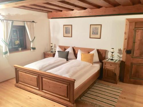 Un dormitorio con una gran cama de madera con sábanas blancas. en Ferienlounge Bluntausee en Golling an der Salzach