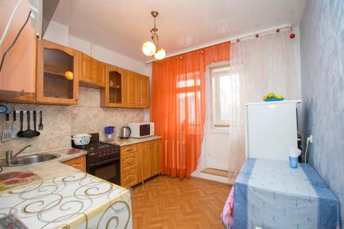 a kitchen with an orange curtain and a refrigerator at Apartment "Уют" in Ufa