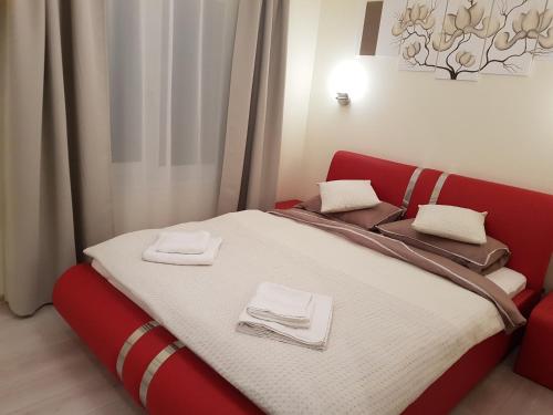 Un dormitorio con una cama roja con toallas. en Apartamentai "Nadiežda" en Palanga