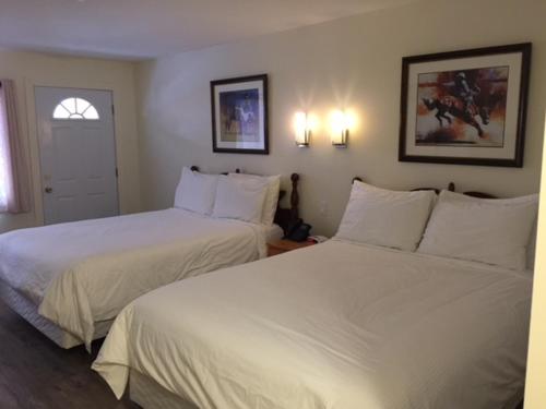Spruce Hill Resort & Spa في 108 Mile Ranch: سريرين في غرفة الفندق ذات شراشف بيضاء