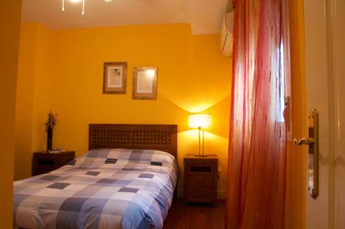 塞维利亚Apartamento San Benito C的卧室里有一张床和一面黄色的墙