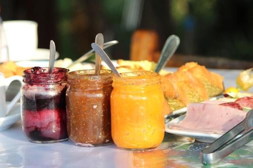 three jars of jam on a table with a plate of food at Kantinho da Serra in Nova Petrópolis