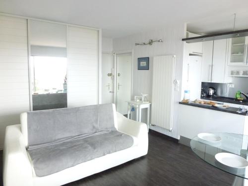 un salon avec un canapé blanc et une cuisine dans l'établissement Résidence le plaisance, à Pornichet