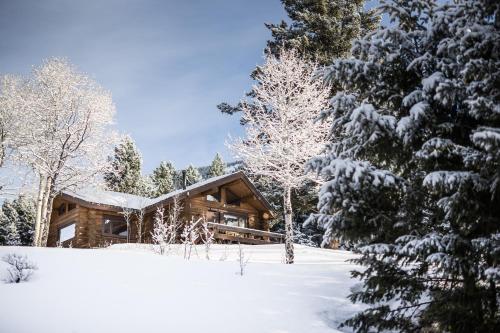 une cabane en rondins dans la neige avec des arbres dans l'établissement Lone Mountain Ranch, à Big Sky