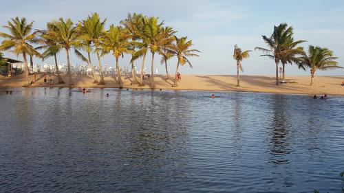a beach with palm trees and a body of water at Pousada Entre as Águas in Imbassai