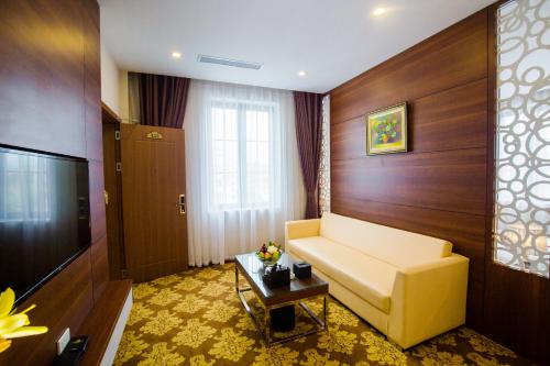 a living room with a couch and a television at Grand Hotel in Hòa Bình