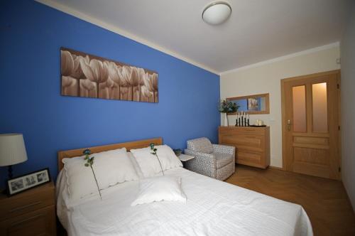 a bedroom with a white bed and a blue wall at Apartmany Alectis in Pec pod Sněžkou