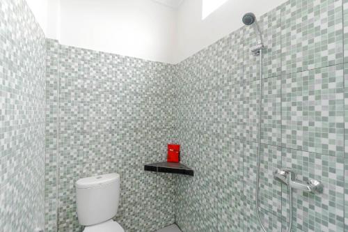 a bathroom with a toilet and a glass shower at RedDoorz Plus near Palembang Square Mall in Palembang