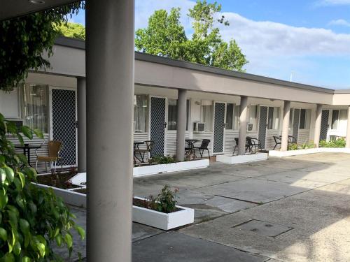 un edificio con mesas y sillas en el patio en Forster Beach Motel en Forster