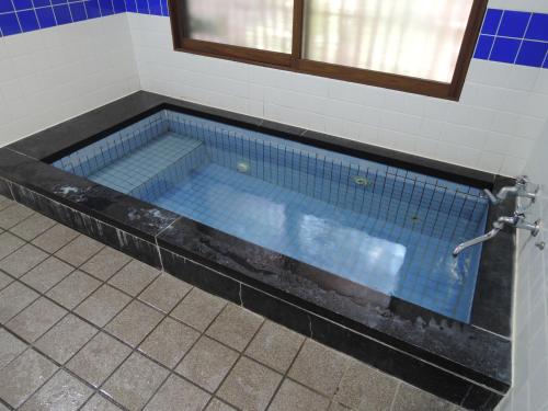 a bath tub in a bathroom with blue tile at Kadokyu Ryokan in Takaoka
