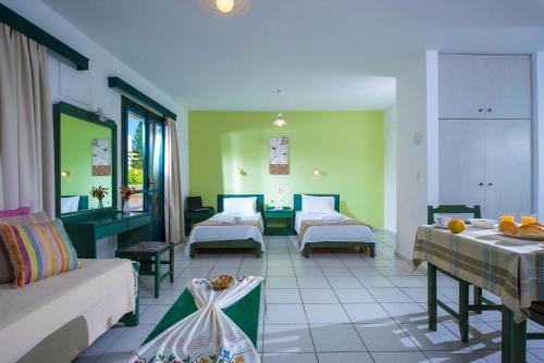 ヘルソニソスにあるGolden Sun Holiday Apts by Estiaのベッド2台とソファが備わるホテルルームです。