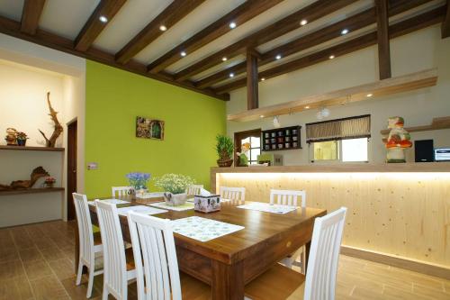 a dining room with a wooden table and white chairs at Kola Garden House in Taitung City