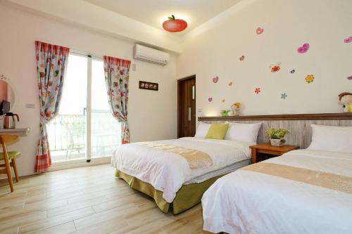 a bedroom with two beds and an apple on the wall at Kola Garden House in Taitung City