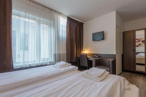 a hotel room with two beds and a window at Hotel Randenbroek in Amersfoort