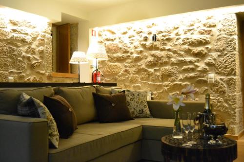 a couch in a living room with a stone wall at Carya Tallaya - Casas de Campo in Vale das Éguas