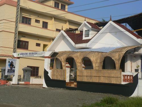 a white building with a balcony in front of a building at Namasthe Ayurveda and Yoga Retreat Cochin in Nedumbassery