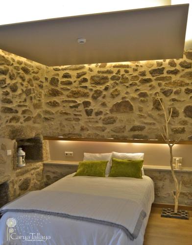 a bedroom with a bed with a stone wall at Carya Tallaya - Casas de Campo in Vale das Éguas