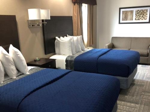 a hotel room with two beds and a chair at Executive Inn and Suites Joaquin in Joaquin